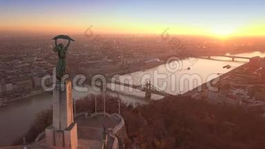 匈牙利布达佩斯-日出时无人驾驶飞机飞越自由女神像上空飞往自由桥的4K空中镜头